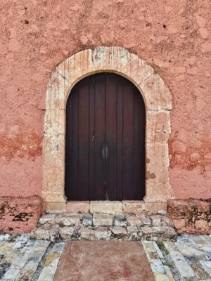 An ancient wooden door framed by vintage stonework showcasing colonial architecture.