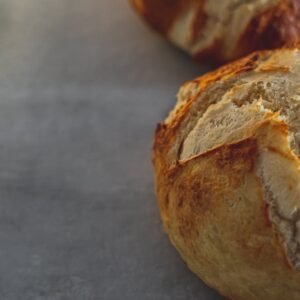 Close-up of freshly baked crusty breads on a rustic table surface, showcasing texture and craftsmanship.