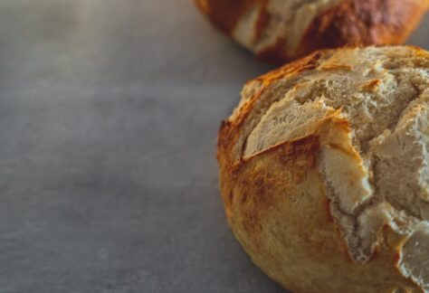 Close-up of freshly baked crusty breads on a rustic table surface, showcasing texture and craftsmanship.